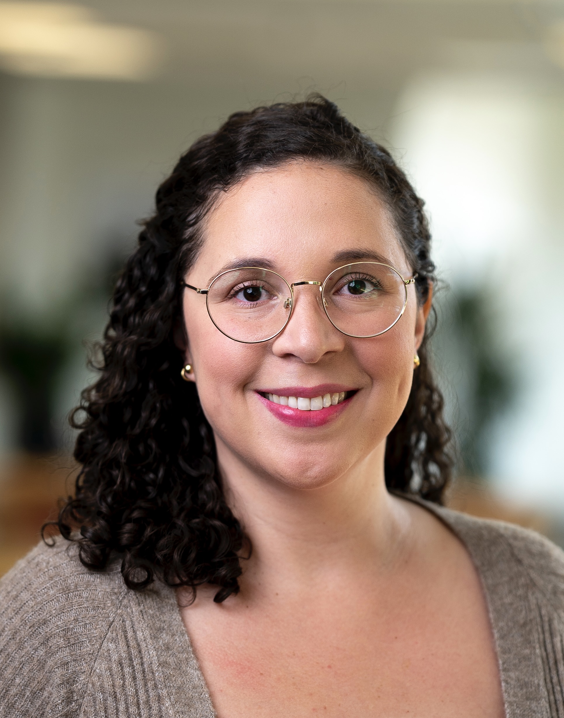 Woman smiling with curly hair wearing glasses